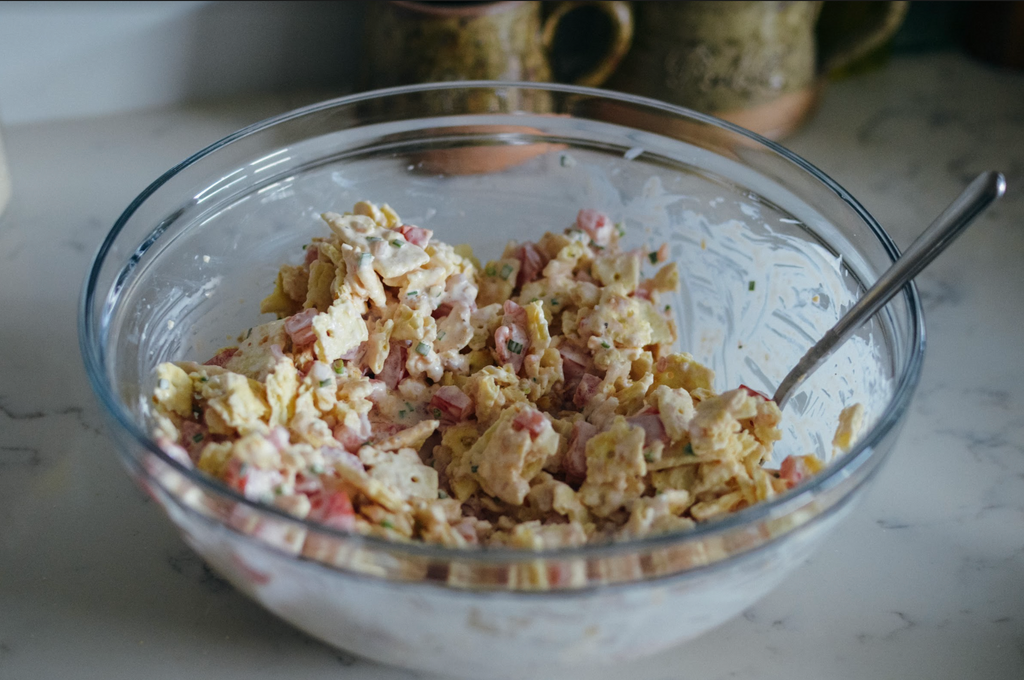 Simple Southern Cracker Salad Recipe- crushed crackers mixed with diced tomato, chopped chives, shallots, mayonnaise, and salt and pepper in glass mixing bowl
