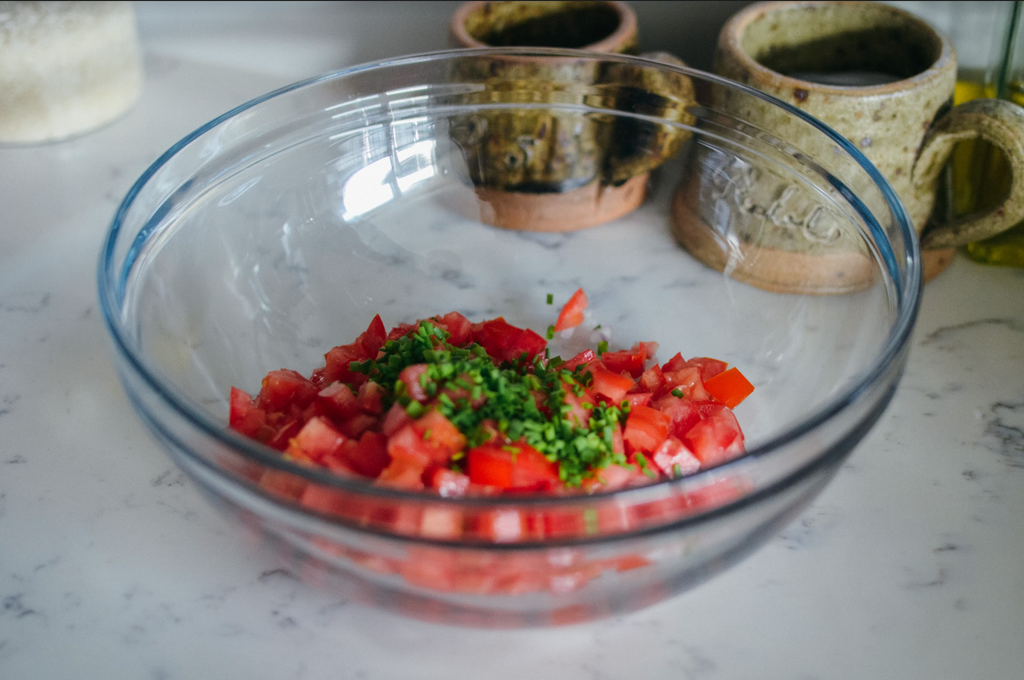 Simple Southern Cracker Salad Recipe- diced tomatoes and chopped chives in glass mixing bowl