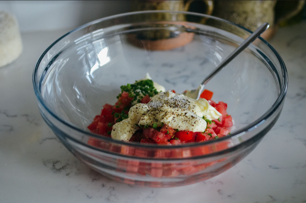 Simple Southern Cracker Salad Recipe- diced tomato, chopped chives, mayonnaise, and salt and pepper in glass mixing bowl