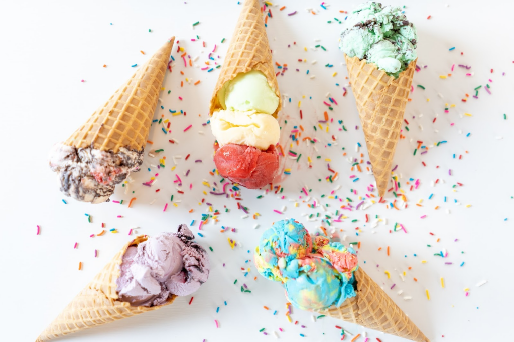 assorted ice cream flavors in cones with sprinkles